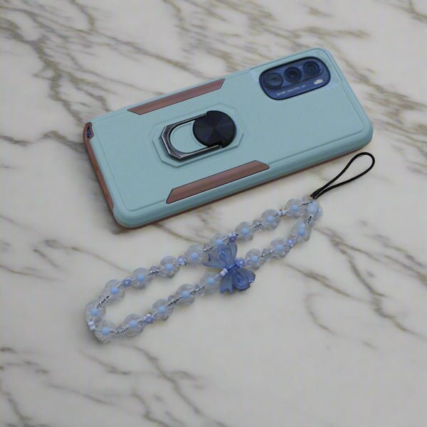 Pastel blue flower phone strap with bow beside a mint green phone on marble surface.