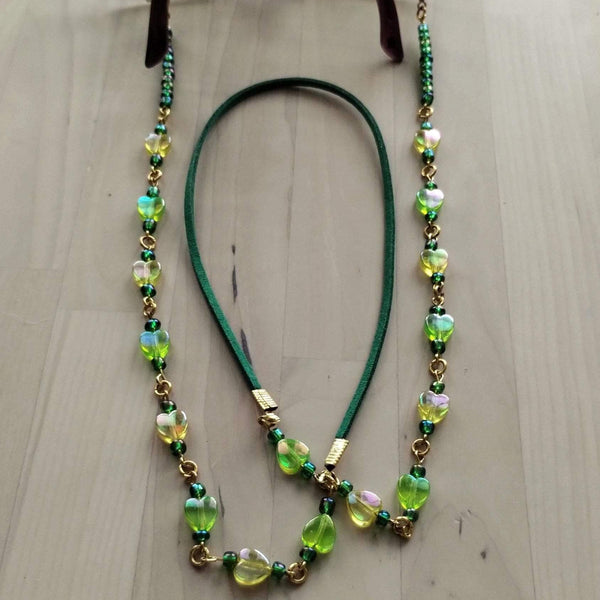 Beaded eyeglasses holder with green and yellow beads. Yellow beads in a heart shape. The middle part is made from soft faux suede for the comfort of your neck