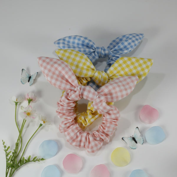 Three colorful scrunchies with bunny ears on a white surface