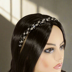 Mannequin head with black hair wearing a decorative crystal headband on a white background