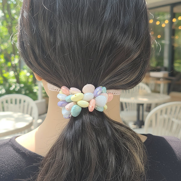 A person shown from behind wearing a pastel shell-shaped hair tie in their dark hair.