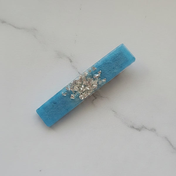 A rectangular turquoise blue resin bar with a textured finish and a central cluster of clear rhinestones, displayed diagonally on a plain white background.