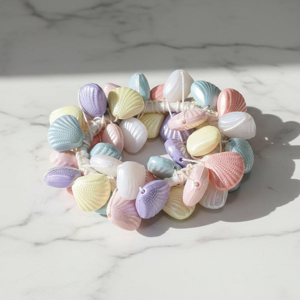 A handmade hair tie made of small pastel-colored seashell-shaped acrylic beads .