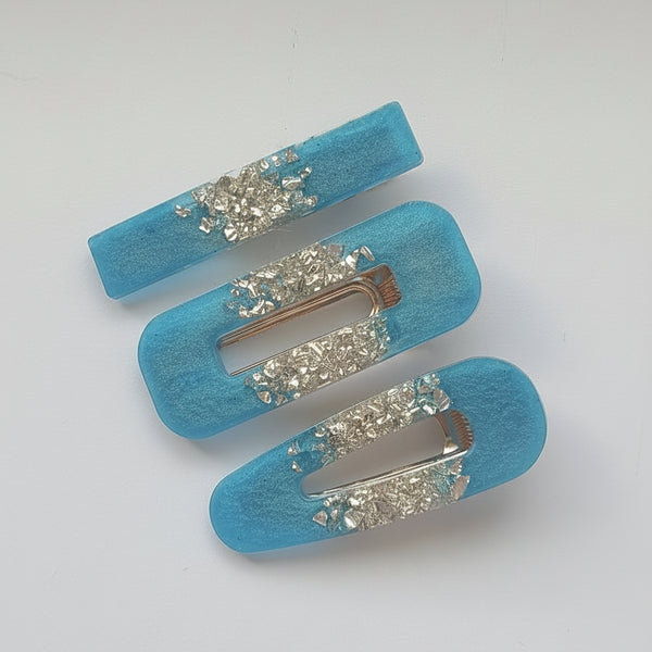 Three light blue felt hair claw clips with silver rhinestone embellishments, arranged diagonally on a plain white background.