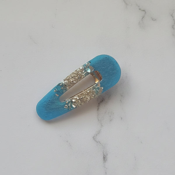 A turquoise blue hair claw clip decorated with silver rhinestones, shown on a plain light gray background.